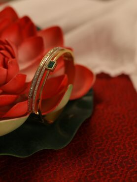 BANGLE BRACELET OF EMERALD CUT GREEN STONE AND TWO PARALLEL ROWS OF CUBIC ZIRCONIA STONES